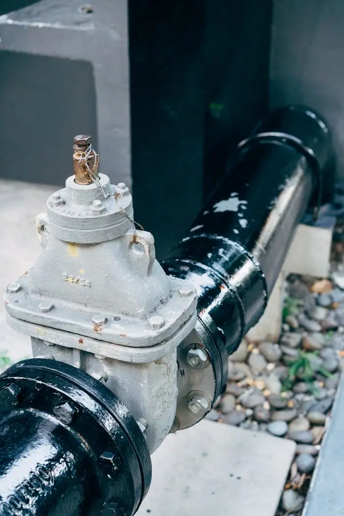 Detailed view of a plumbing valve with connected black pipeline, essential for industrial applications.