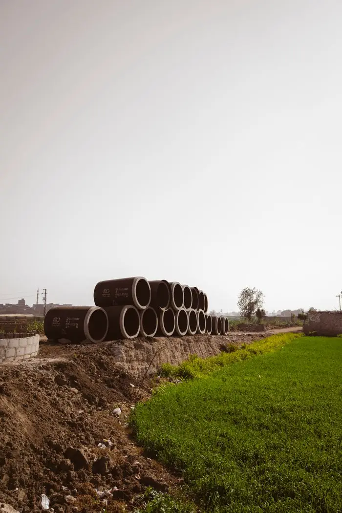 Large concrete pipes stacked in a rural landscape, ready for construction or drainage.